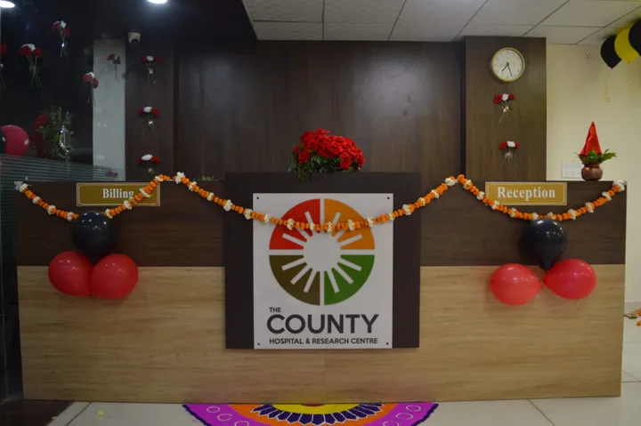 The reception and billing counter, dressed with marigold garlands and a rangoli beneath the hospital logo