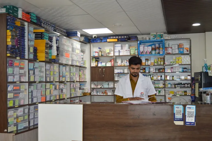 A pharmacist working at the in-house medical store, with medicines stacked floor to ceiling behind him