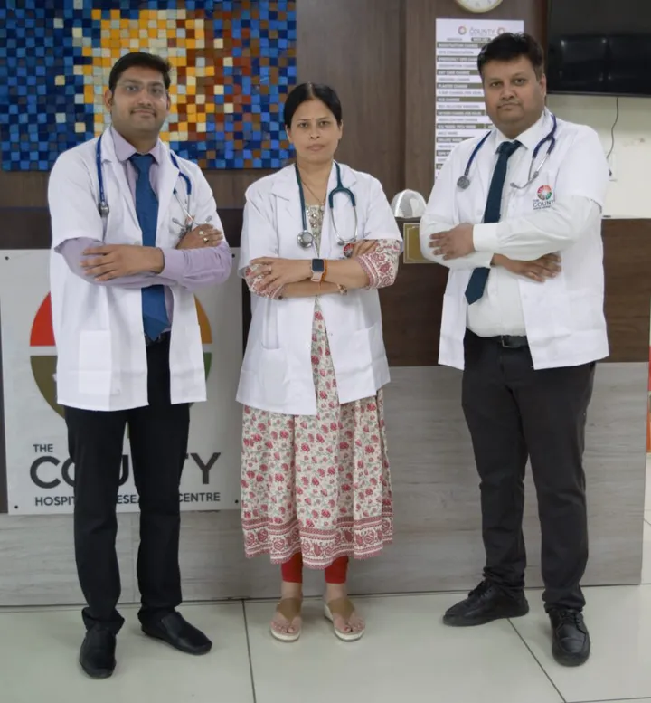 Three consultants in white coats standing together in front of the reception desk