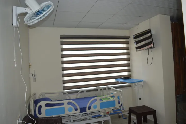 A private room with an adjustable bed, wall-mounted television, ceiling fan and oxygen point