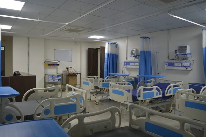 A ward bay with several adjustable beds, wall-mounted monitors and a nursing station