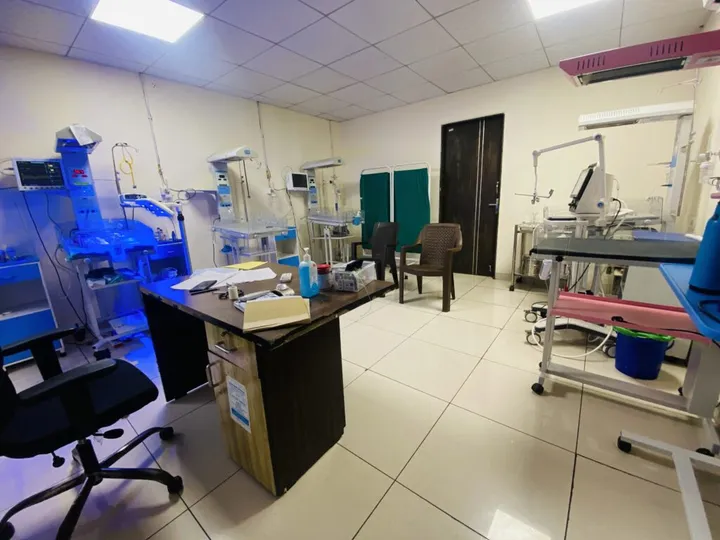 The neonatal intensive care unit, with incubators, radiant warmers and a phototherapy unit casting blue light