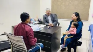 A senior doctor in consultation with a mother and her small child during a health camp
