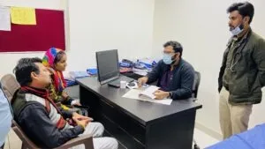 A doctor consulting a boy and his mother across the desk during a free check-up camp