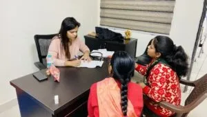 A woman doctor taking notes while consulting a mother and daughter at a health camp