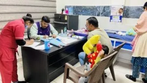 Staff registering families at the camp desk while a child waits with a soft toy