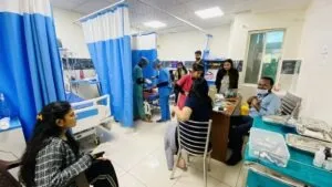 A busy ward bay during a camp day, with patients on curtained beds and staff moving between them