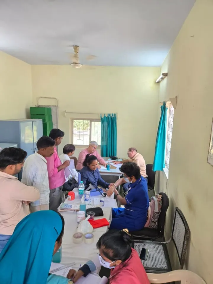 A nurse taking a patient’s blood pressure at an outreach camp while others wait their turn at the screening table